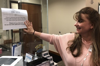 caption: Tove Skaftun, the chief nursing officer for the Community Health Center of Snohomish County, points out a sign warning people who could have been exposed to the new coronavirus from China to identify themselves.
