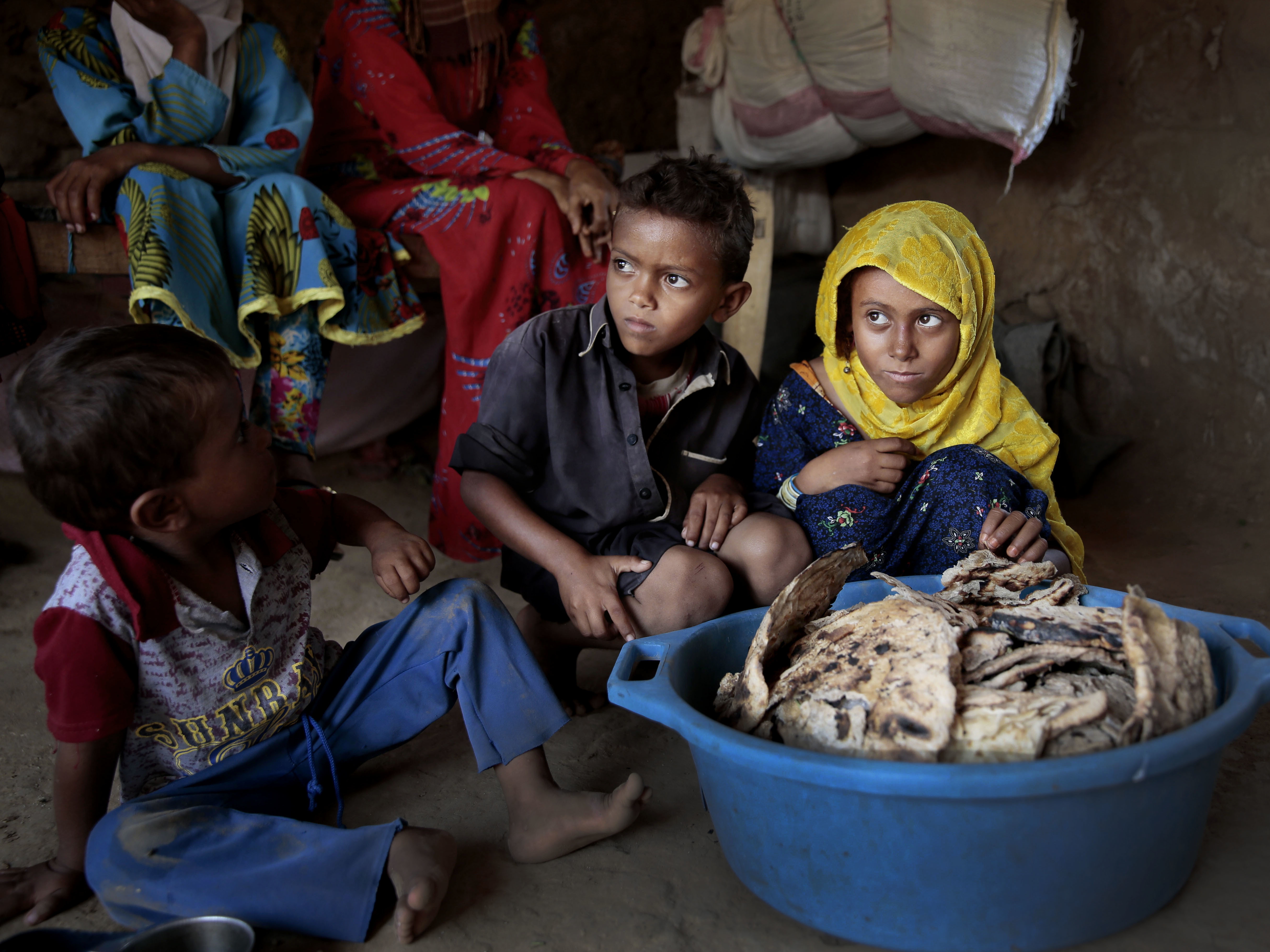caption: Children sit in front of a tub of moldy bread in their shelter in Aslam, Hajjah, Yemen, last month. The U.N. has estimated that up to 14 million Yemenis — about half the country's population — will suffer severe food shortages in the next few months.