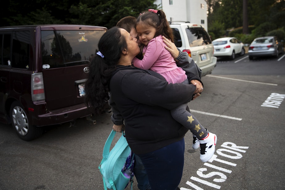 caption: Tynikki and Sean hug Vay, 5, before she gets on the school’s for her first day of school, on Monday, September 12, 2022, outside of their apartment complex. 