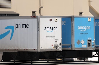 caption: Amazon delivery trucks are parked in Richmond, Calif., on June 21.