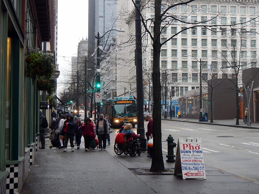 caption: A line of homeless people outside a shelter in downtown Seattle.