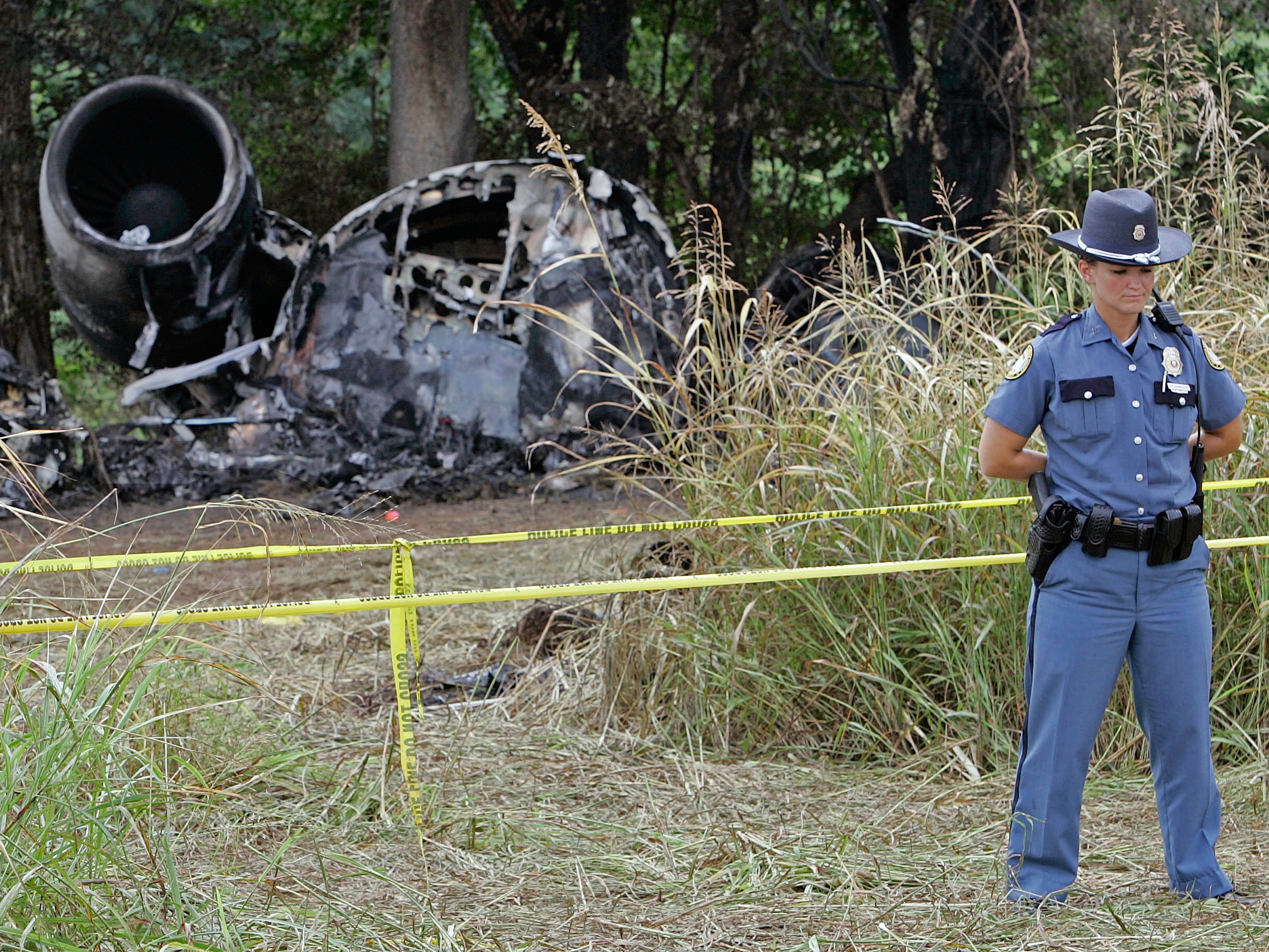 caption: In this Aug. 29, 2006, photo, a police officer guards the wreckage of Comair Flight 5191 at Blue Grass Airport in Lexington, Ky. The crash killed 49 passengers and crew.