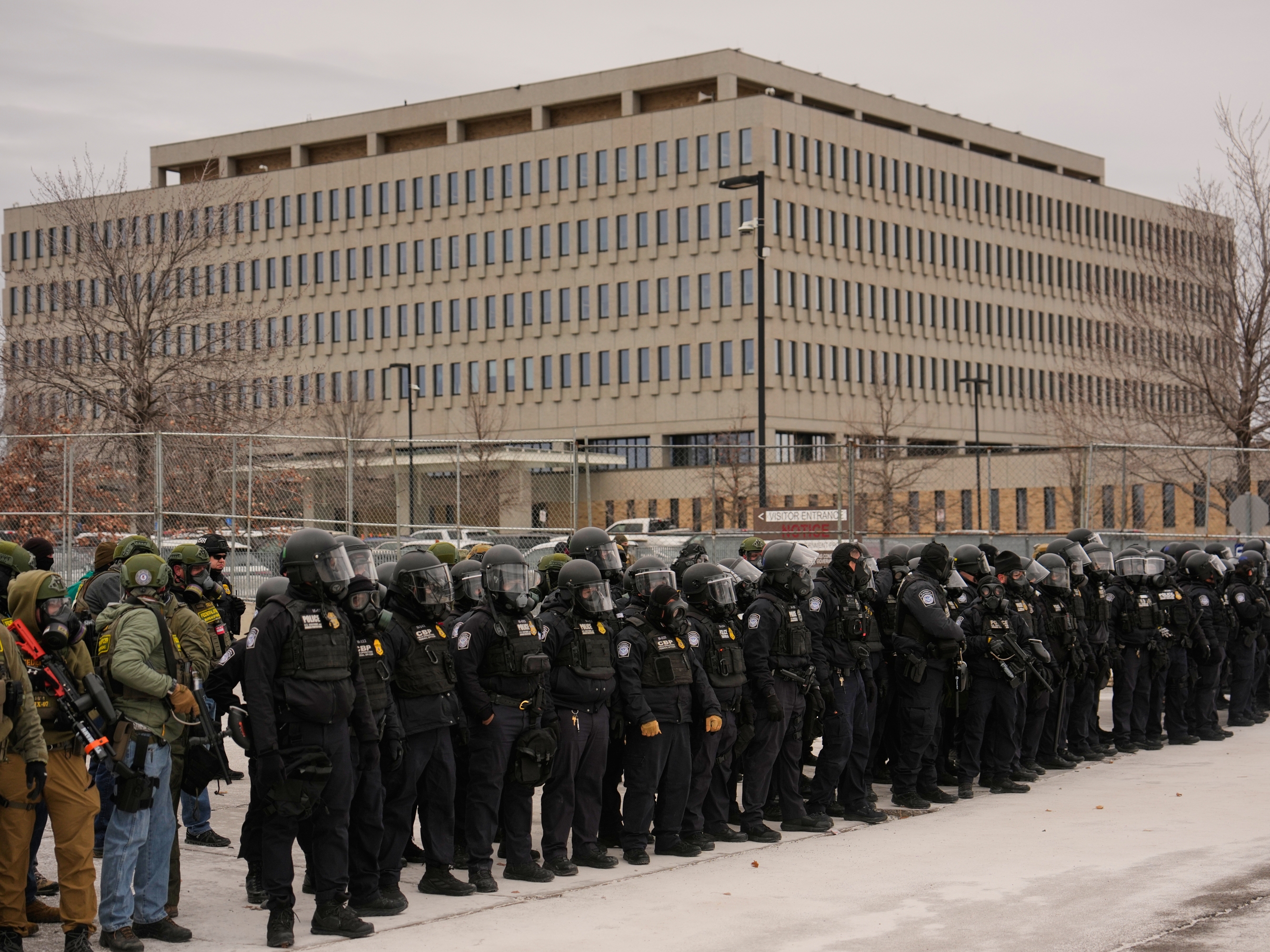 caption: Federal immigration officers outside Bishop Henry Whipple Federal Building, Thursday in Minneapolis.