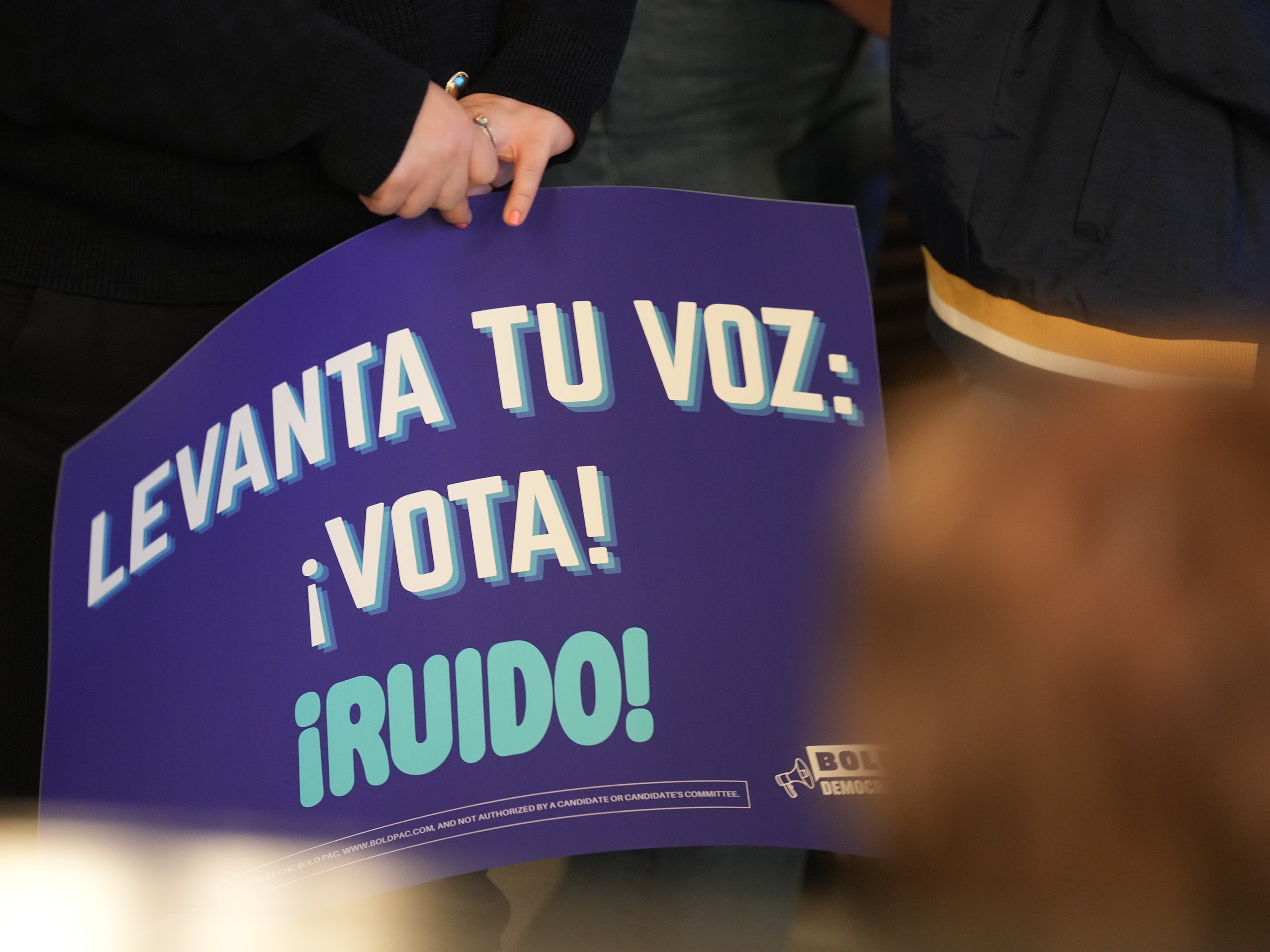 caption: A person holds a sign saying "Raise your voice: Vote" at a creator event for BOLD Democrats, a Hispanic PAC, in Houston on Feb. 17. Democrats think they may have a chance to sway Latino voters who supported President Trump two years ago.