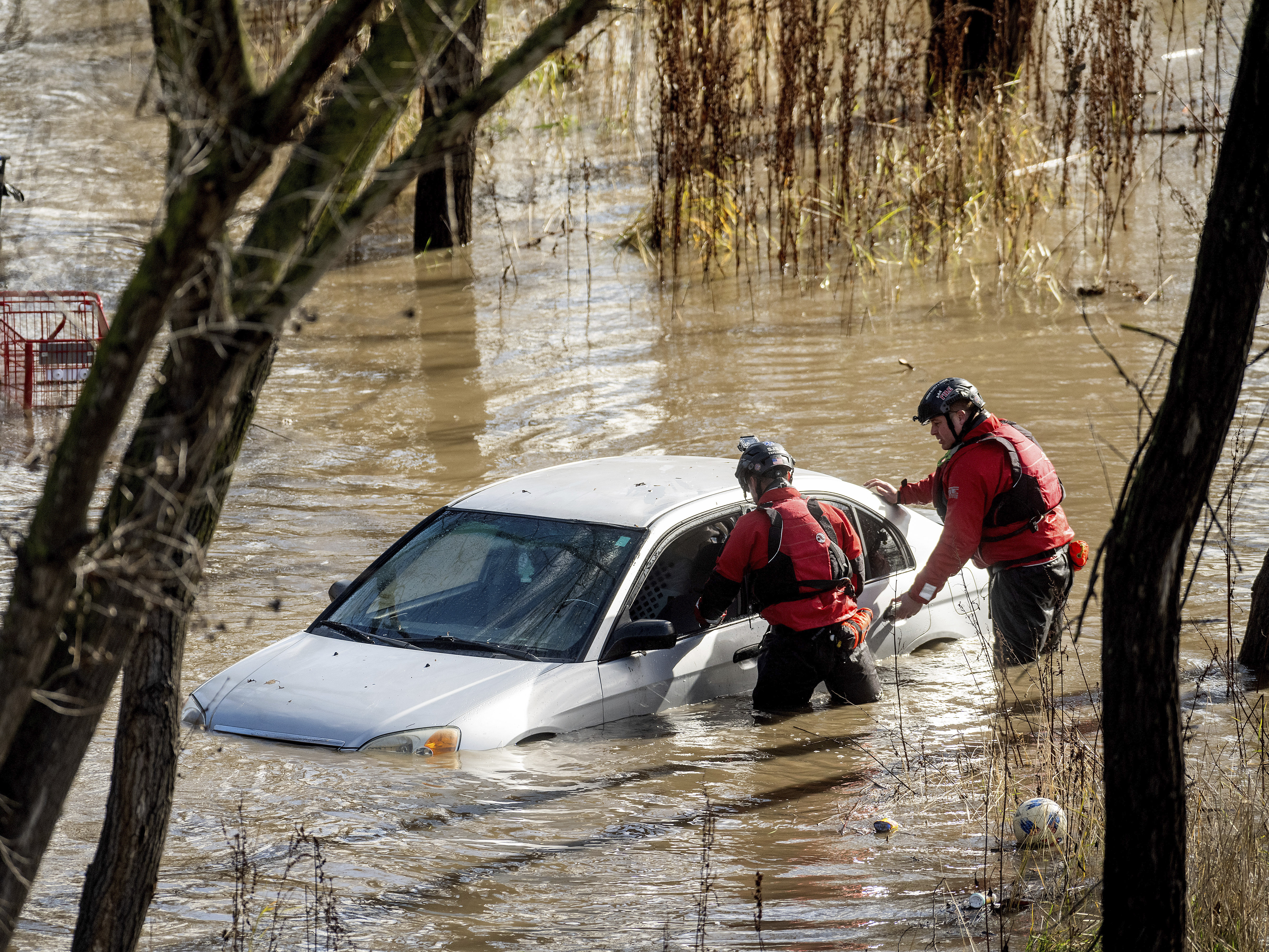 caption: San Jose: Search and rescue workers check a car trapped in flooding after heavy rain caused the Guadalupe River to overflow its banks, Sunday.