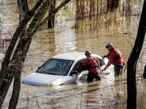 caption: San Jose: Search and rescue workers check a car trapped in flooding after heavy rain caused the Guadalupe River to overflow its banks, Sunday.