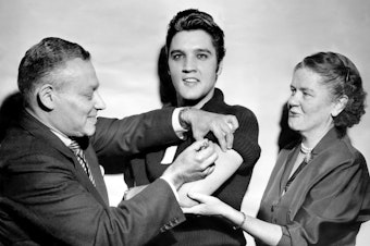caption: Elvis Presley got his polio vaccination from Dr. Harold Fuerst and Dr. Leona Baumgartner at CBS' Studio 50 in New York City on Oct. 28, 1956. The chart-topping singer took part in a March of Dimes campaign to convince teens to get vaccinated.