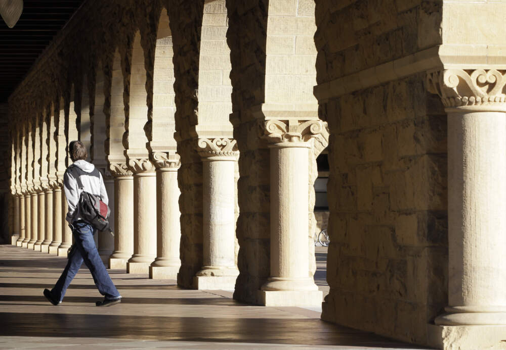 caption: A Stanford University student walks though the halls of the Stanford University campus in Palo Alto, California. (Paul Sakuma/AP)