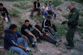 caption: A U.S. Border Patrol agent processes a group of migrants in Sunland Park, New Mexico. Democratic lawmakers and immigrant advocates are urging President Biden to end Title 42 border restrictions.