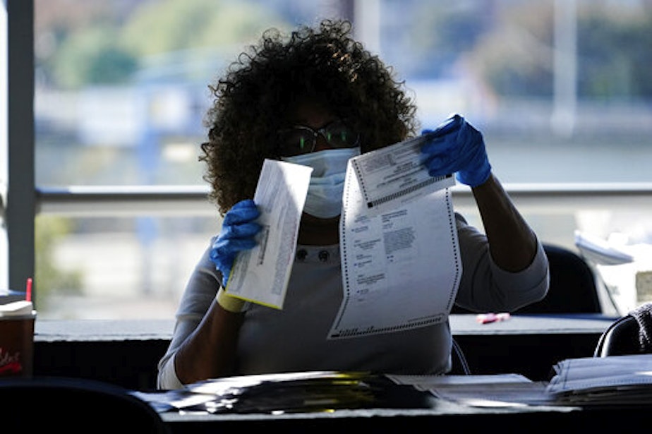 caption: An election personnel examines a ballot as vote counting in the general election continues at State Farm Arena, Wednesday, Nov. 4, 2020, in Atlanta.