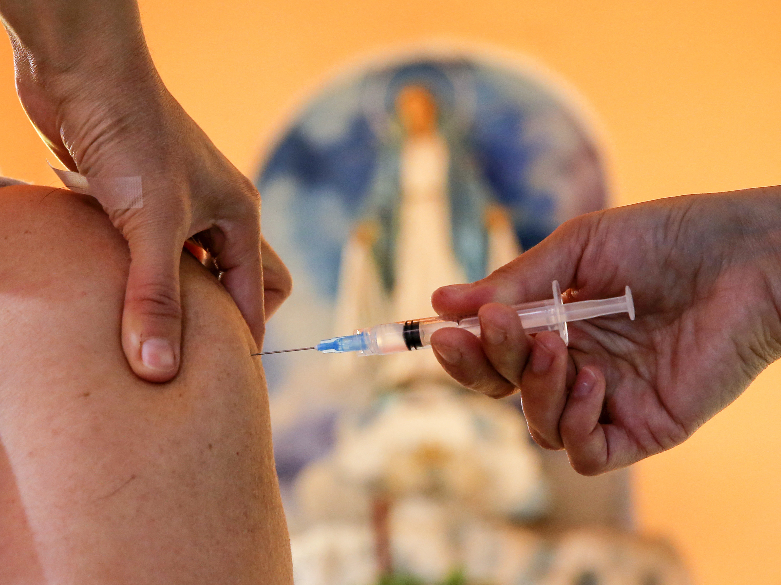 caption: A health worker administers a dose of the Pfizer BioNTech vaccine against COVID-19, at the Medalla Milagrosa Church in Valparaiso, Chile, on April 6.