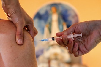 caption: A health worker administers a dose of the Pfizer BioNTech vaccine against COVID-19, at the Medalla Milagrosa Church in Valparaiso, Chile, on April 6.