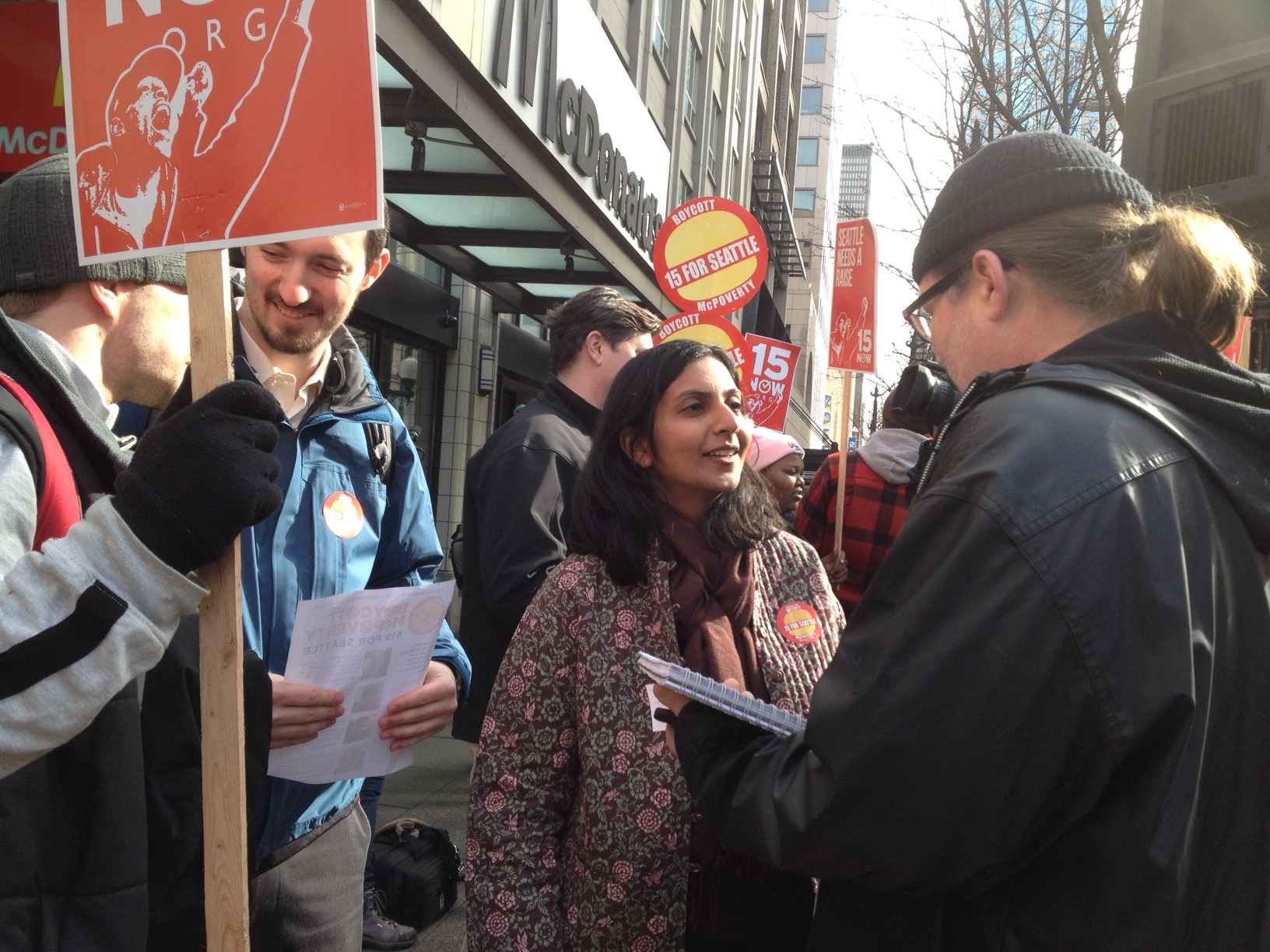 caption: Seattle City Councilmember Kshama Sawant talks with a fan outside McDonald's restaurant in downtown Seattle at the McPoverty protest on Thursday, February 20.