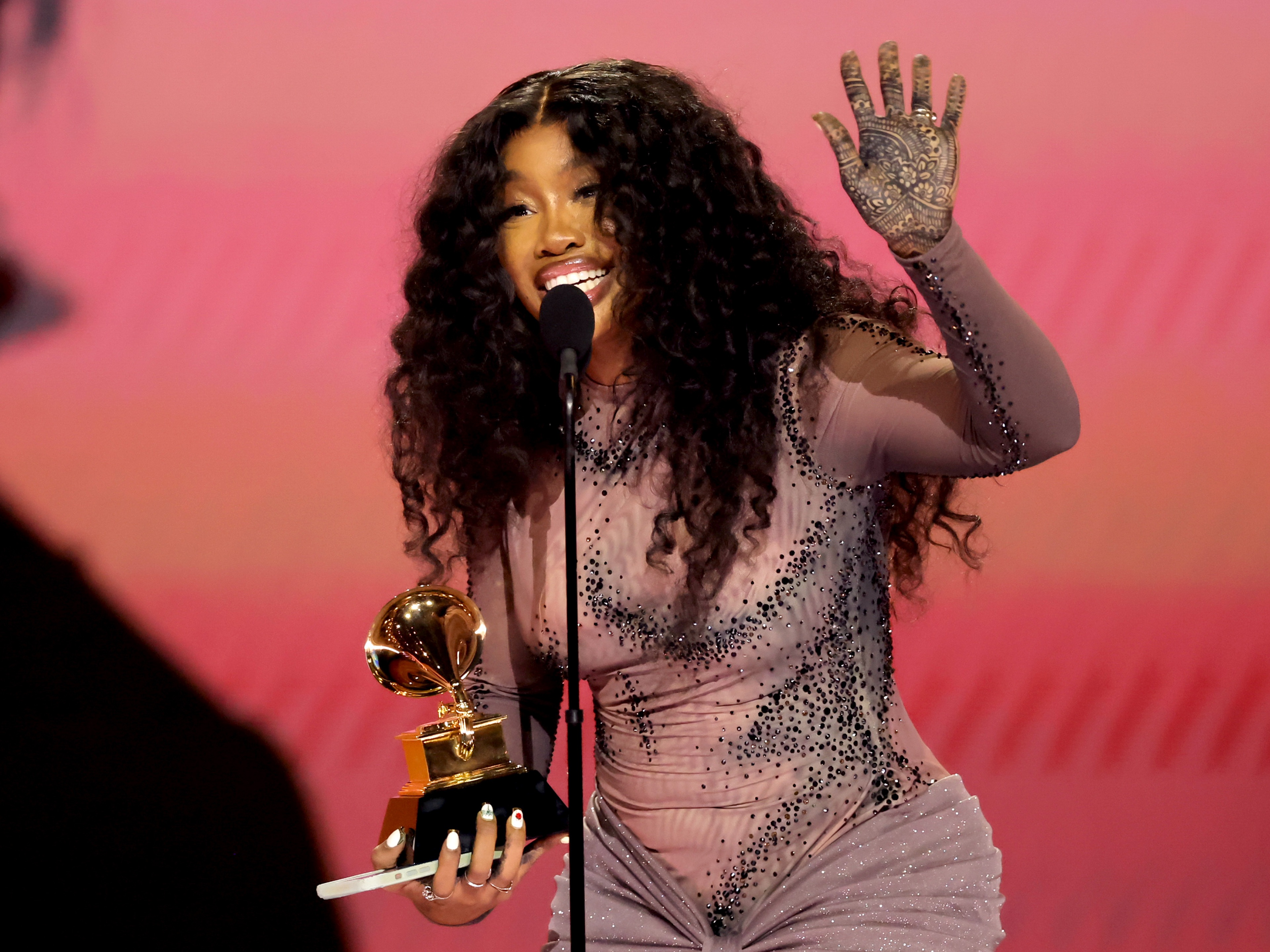caption: SZA accepts a Grammy Award for best R&amp;B song for "Snooze" on February 4, 2024. At that point, the album on which "Snooze" appears, <em>SOS</em>, was already 14 months old. This week, nearly 11 months after the Grammys, <em>SOS</em> has returned to the top of the <em>Billboard</em> album chart thanks to the release of a deluxe version.