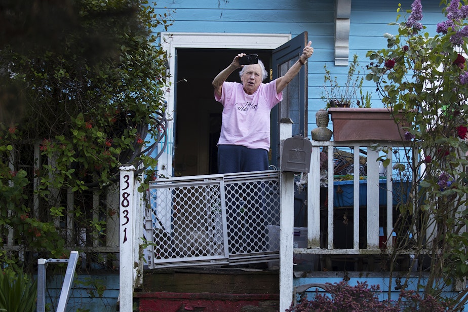 caption: A Wallingford resident cheers and gives a thumbs up for the Seattle Quarantine Parade as it drives through the neighborhood on Friday, May 8, 2020, in Seattle. 