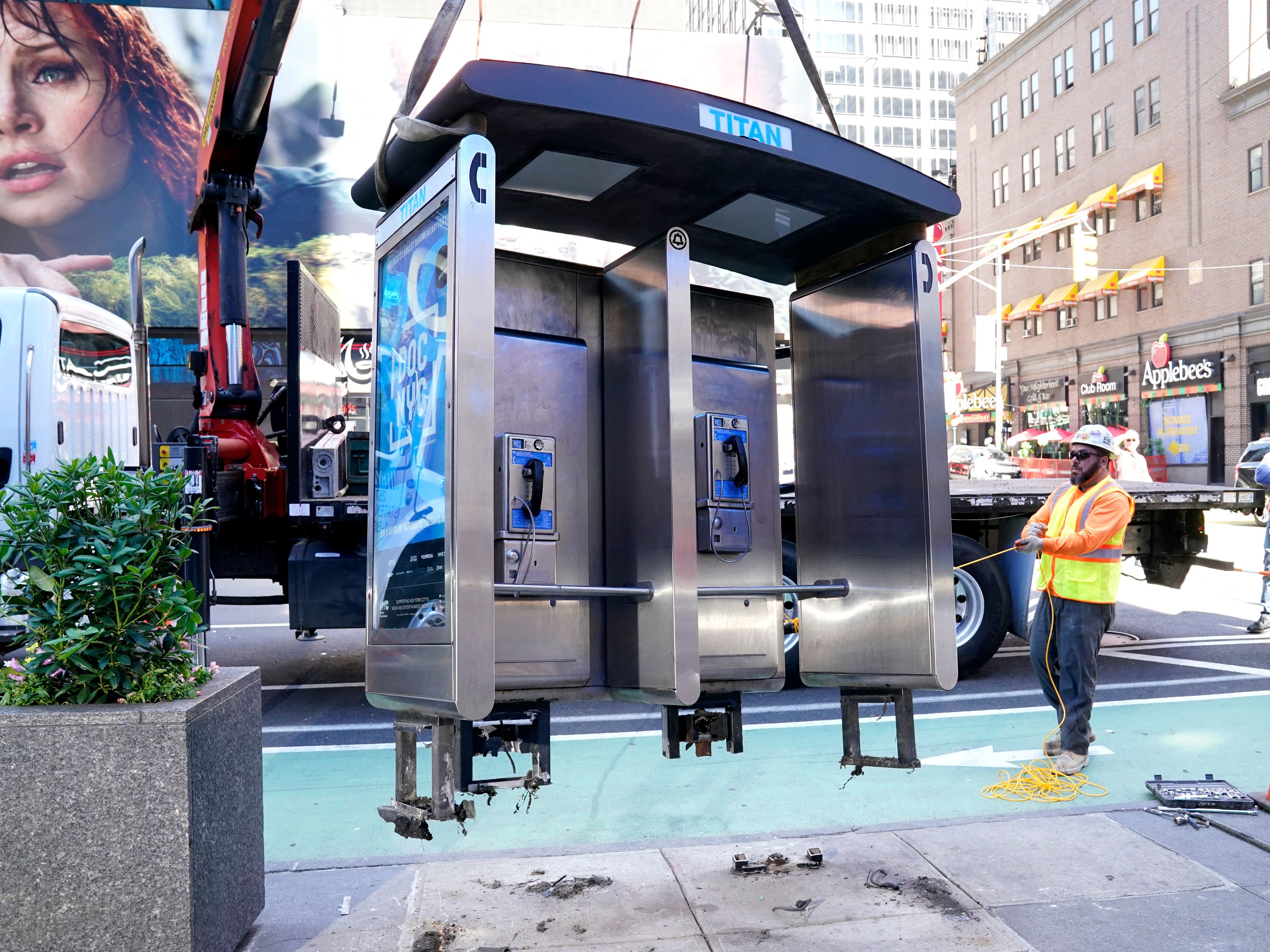 caption: Workers remove the final New York City pay phone near Seventh Avenue and 50th Street in Midtown Manhattan on Monday. Despite the fanfare, there are still some pay phones standing in the city.
