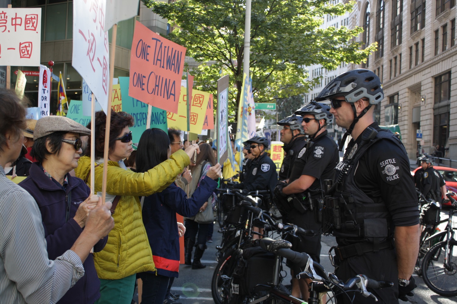 caption: Demonstrator Alice Tsai takes a photo of the police blocking her group from accessing the Westin Hotel, where Chinese President Xi Jinping is staying.