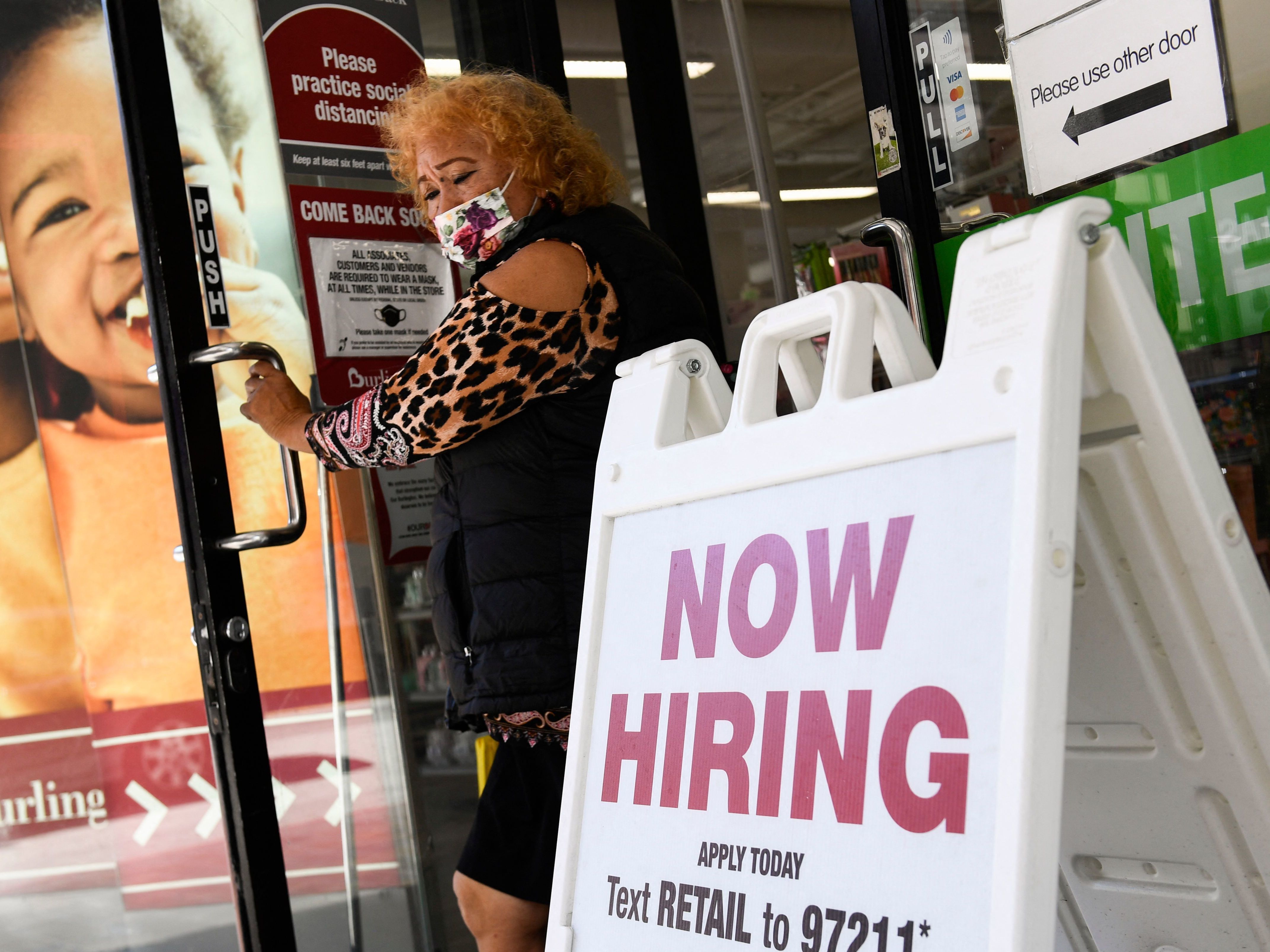 caption: A 'now hiring' sign is displayed outside of a Burlington Coat Factory retail store in downtown Los Angeles on March 11.