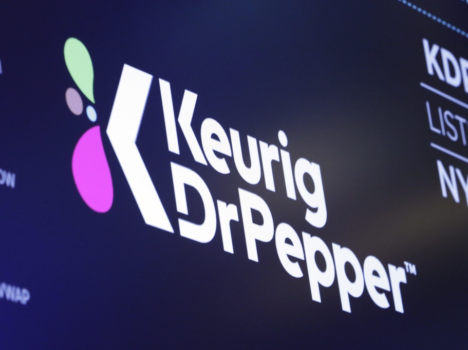 caption: The logo for Keurig Dr. Pepper appears in July 2018 above a trading post on the floor of the New York Stock Exchange.