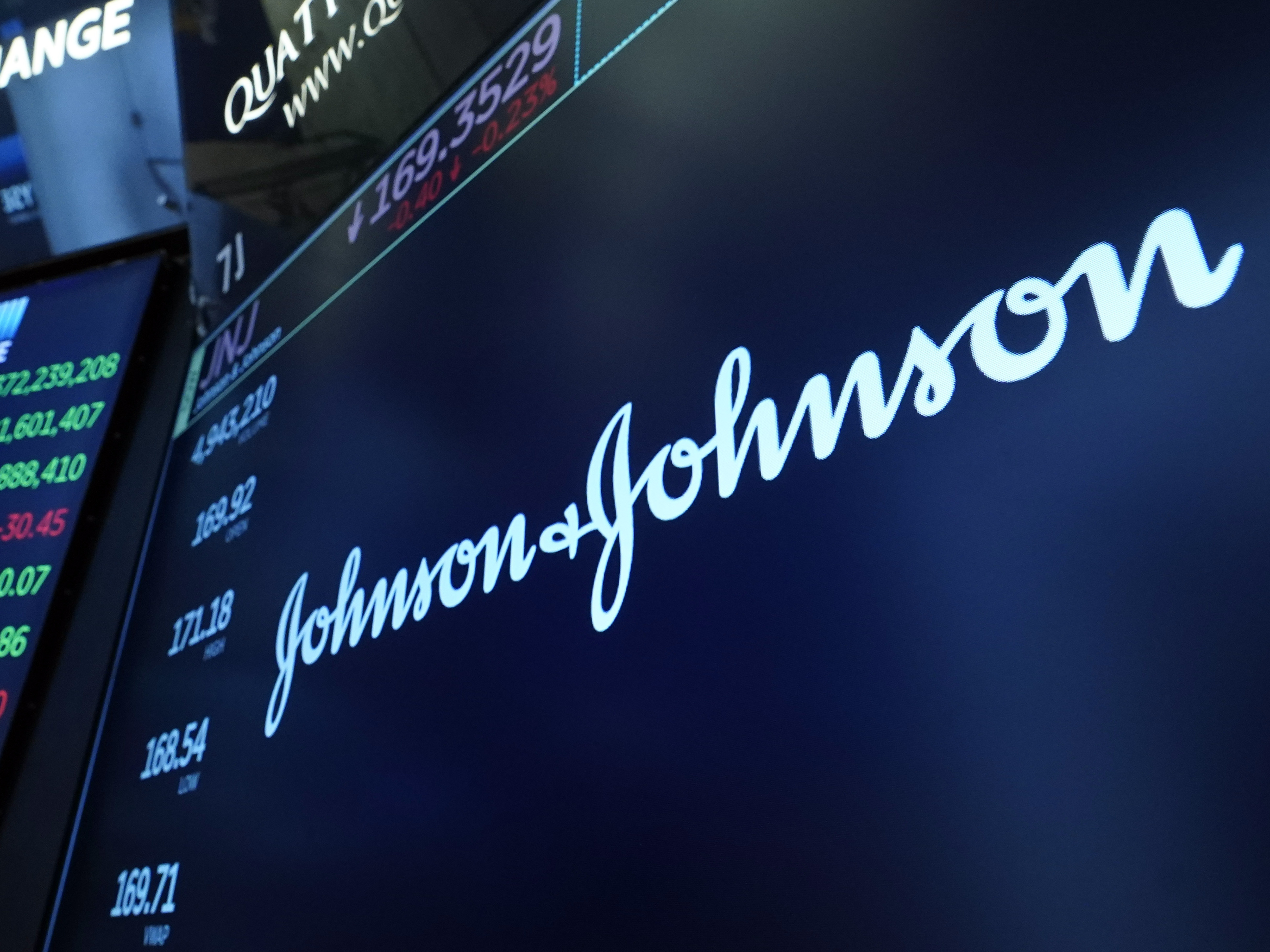caption: The Johnson & Johnson logo appears above a trading post on the floor of the New York Stock Exchange on July 12, 2021.