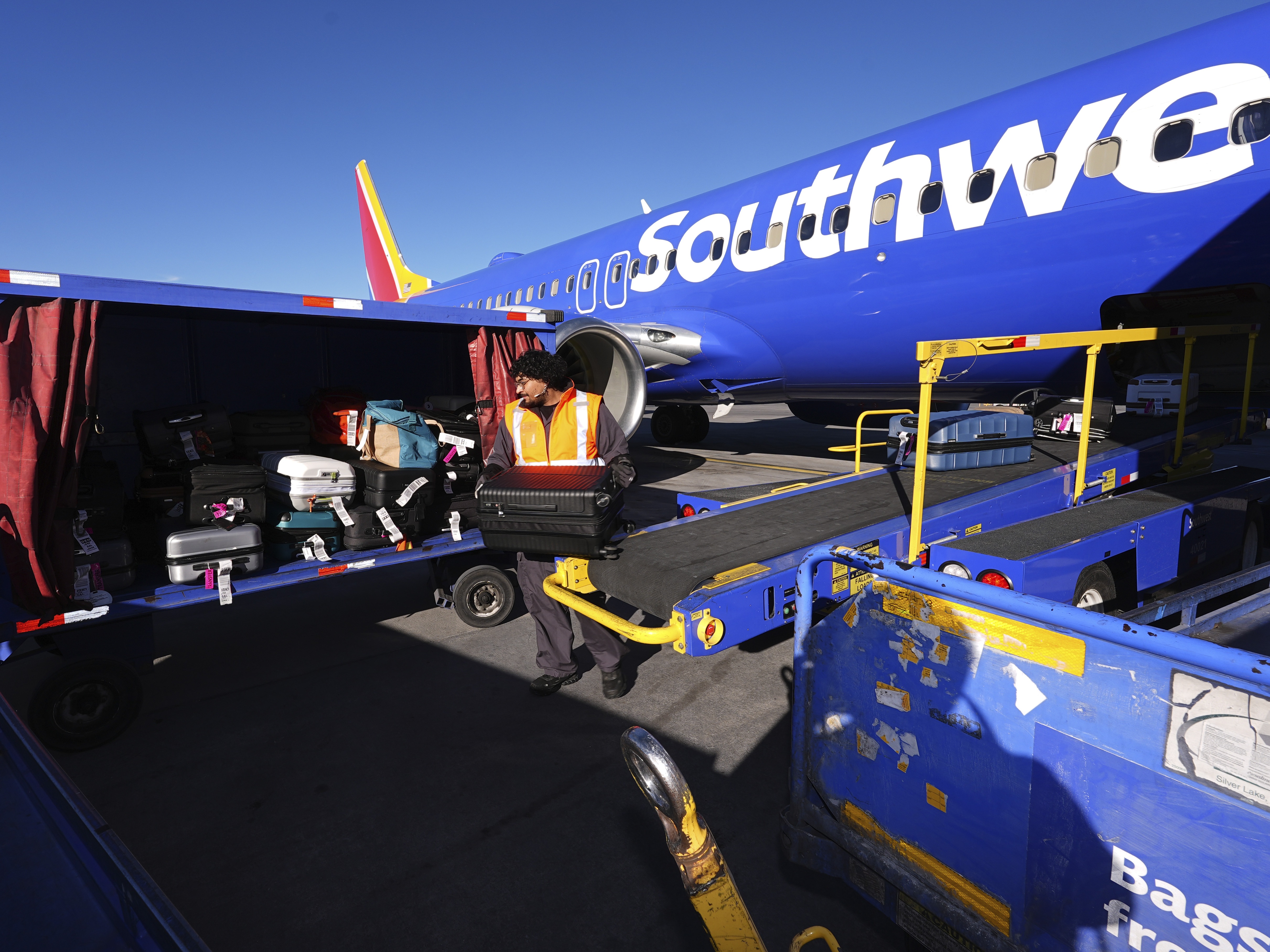 caption: A Southwest Airlines plane is unloaded at Denver International Airport on Thursday, Feb. 27. The airline announced that it would begin charging some passengers to check bags.