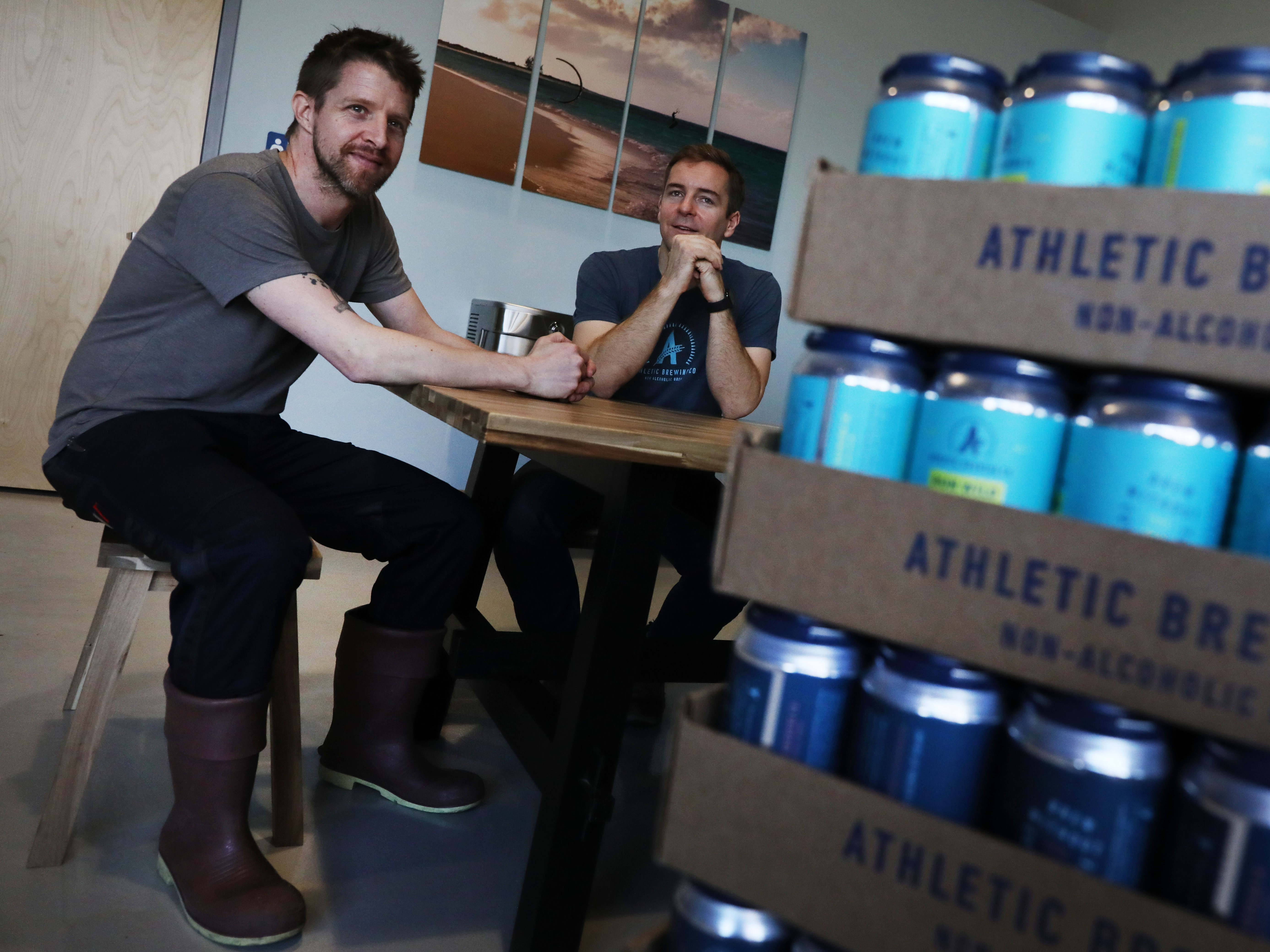 caption: Athletic Brewing Co. co-founders Bill Shufelt (right) and John Walker, here at the company's production plant in Stratford, Conn., have created a range of high-quality nonalcoholic beers to provide people more options when they're out socializing.