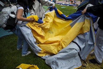 caption: University of Washington students pack up a tent and belongings after an agreement between protesters and the University to remove the encampment, on Friday, May 17, 2024, in Seattle. 