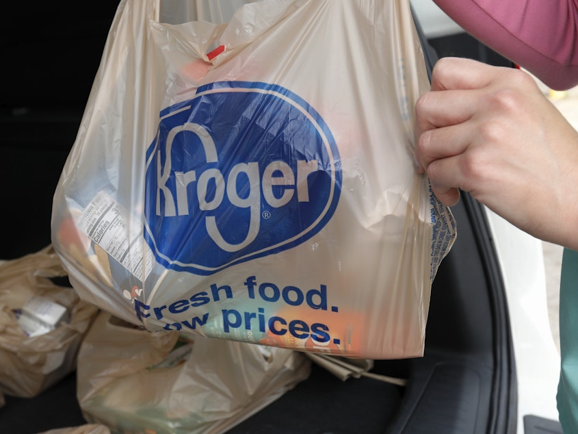 A shopper packs groceries from Kroger into a car.