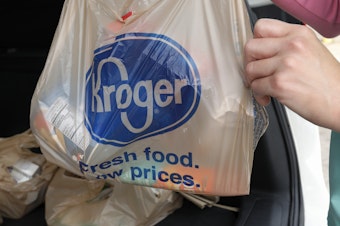 A shopper packs groceries from Kroger into a car.