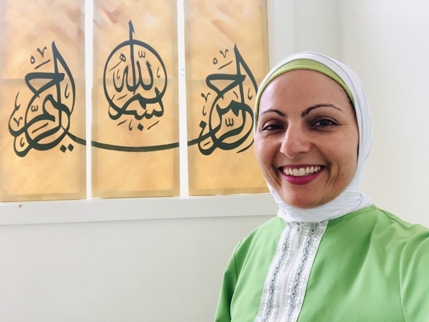 caption: Aneelah Afzali is the executive director of the American Muslim Empowerment Network, A program of the Muslim Association of Puget Sound. The writing behind her says "In the name of God, the Most Gracious, the Most Merciful."