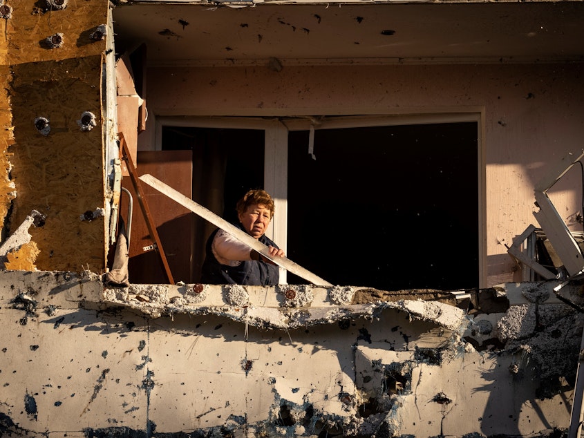 caption: A resident cleans her balcony in an apartment building damaged by shelling in Kyiv on Tuesday.