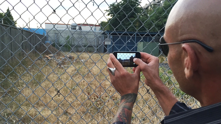 caption: A Ballard man snaps a photo of a vacant lot that may one day host a tent city for the homeless.
