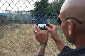 caption: A Ballard man snaps a photo of a vacant lot that may one day host a tent city for the homeless.