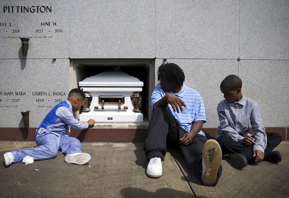 caption: Jeffries Butts, center, the father of two of Lyles' children, sits with family members next to the casket of Charleena Lyles during a burial ceremony at Hillcrest Burial Park on Monday, July 10, 2017, in Kent. Lyles was killed by Seattle police.