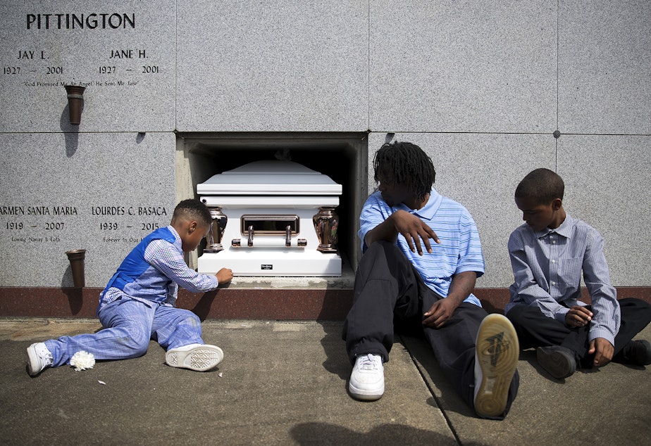 caption: Jeffries Butts, center, the father of two of Lyles' children, sits with family members next to the casket of Charleena Lyles during a burial ceremony at Hillcrest Burial Park on Monday, July 10, 2017, in Kent. Lyles was killed by Seattle police.