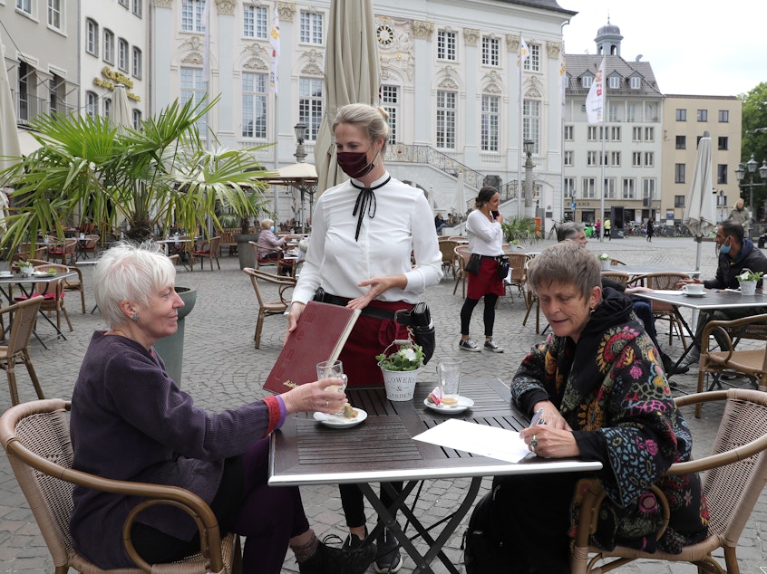 caption: Outdoor dining in Bonn. Indoor dining is riskier than outdoor meals, say the experts. Outdoor air can disrupt viral particles that have been expelled.