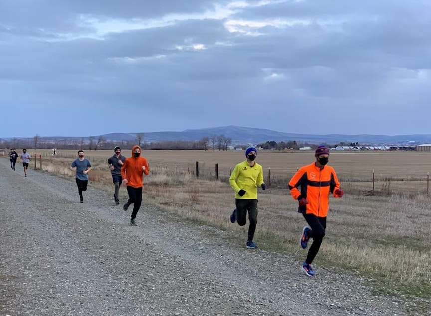 caption: Ellensburg High School coach Jeff Hashimoto, in orange, leads masked cross-country team members on a long training run on February 8.