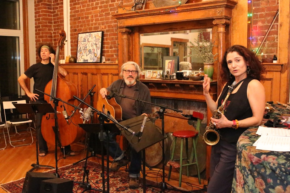 caption: Jim Page (center), Jessica Lurie (right) and Mark Ettinger (left) performed songs about Seattle and Amazon for a rapt New York audience