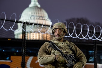 caption: A member of the Virginia National Guard stands outside the razor wire fencing surrounding the U.S. Capitol on Friday. Up to 25,000 troops are expected by Inauguration Day.