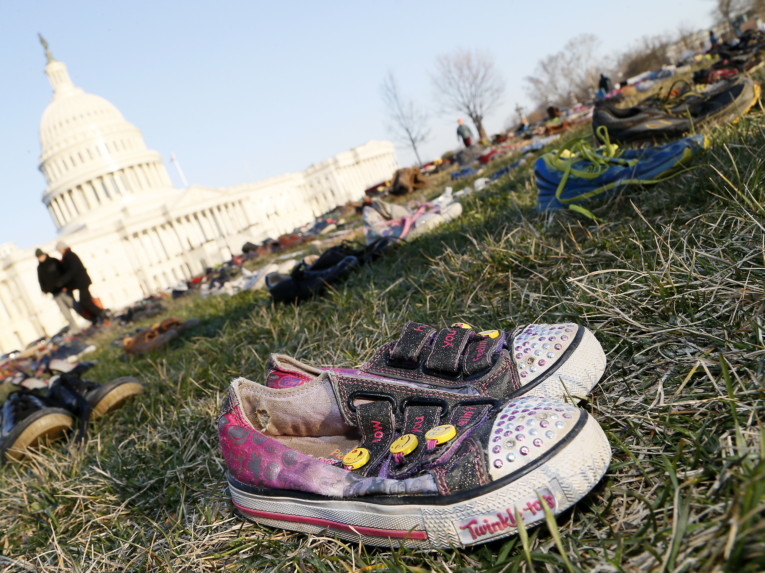 caption: Thousands of empty empty pairs of shoes for every child killed by guns in the U.S. since Sandy Hook cover the southeast lawn of U.S. Capitol on March 13, 2018, in Washington, D.C.