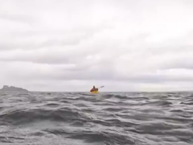 caption: A screenshot of a video from the Associated Press shows Adrián Simancas kayaking in the Strait of Magellan, moments before a whale surfaced and briefly engulfed him.