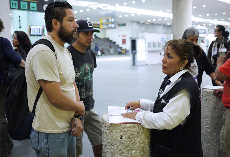 caption: Gustavo Lavariega, a volunteer with Deportees United, talks with an official from Mexico's labor department as he waits for deportees to arrive on a flight from Texas.