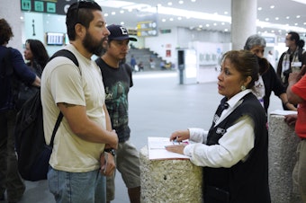 caption: Gustavo Lavariega, a volunteer with Deportees United, talks with an official from Mexico's labor department as he waits for deportees to arrive on a flight from Texas.