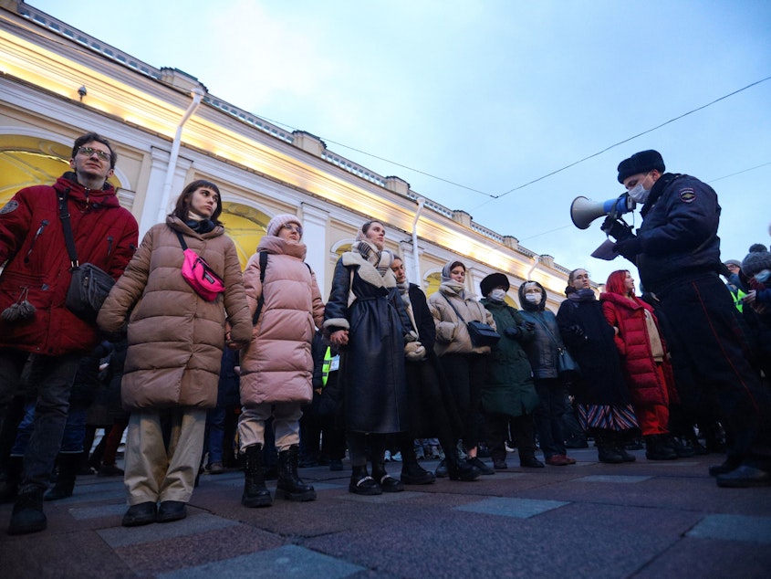 caption: A police officer uses a loudspeaker to address people gathered in St. Petersburg to protest Russia's invasion of Ukraine on Feb. 24.