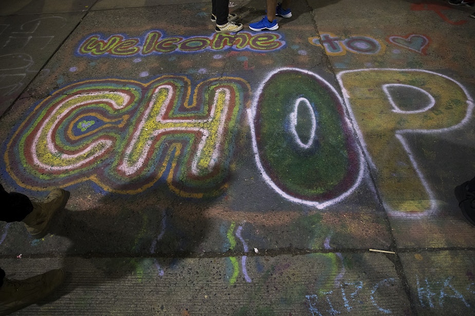 caption: Welcome to CHOP, (Capitol Hill Occupied Protest), is spray painted on the pavement at the intersection of 11th Avenue and East Pine Street on Saturday, June 13, 2020, in Seattle. 