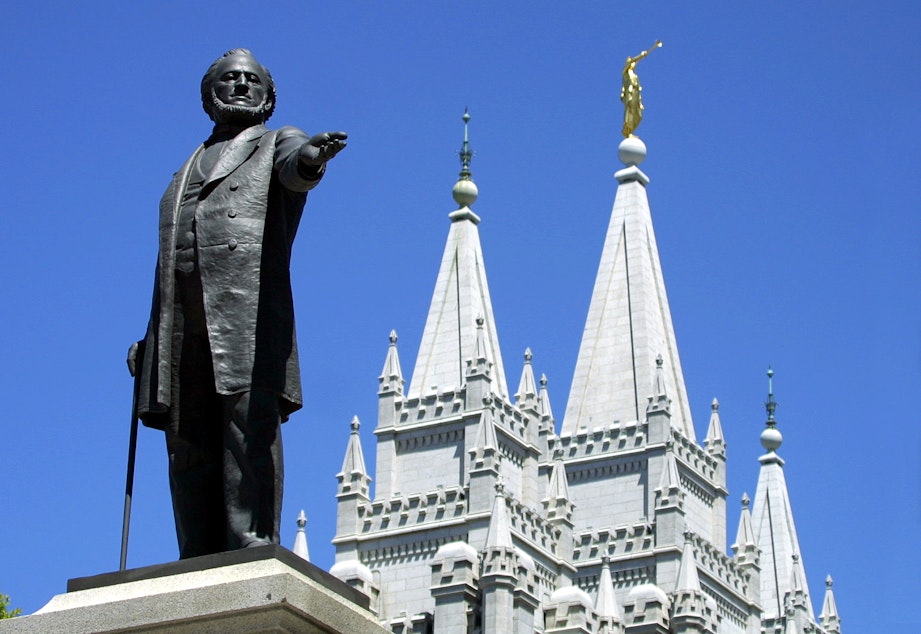 caption: A statue of Brigham Young, second president of the Church of Jesus Christ of Latter Day Saints stands in the center of Salt Lake City with the Mormon Temple spires in the background 19 July 2001. (George Frey/AFP via Getty Images)