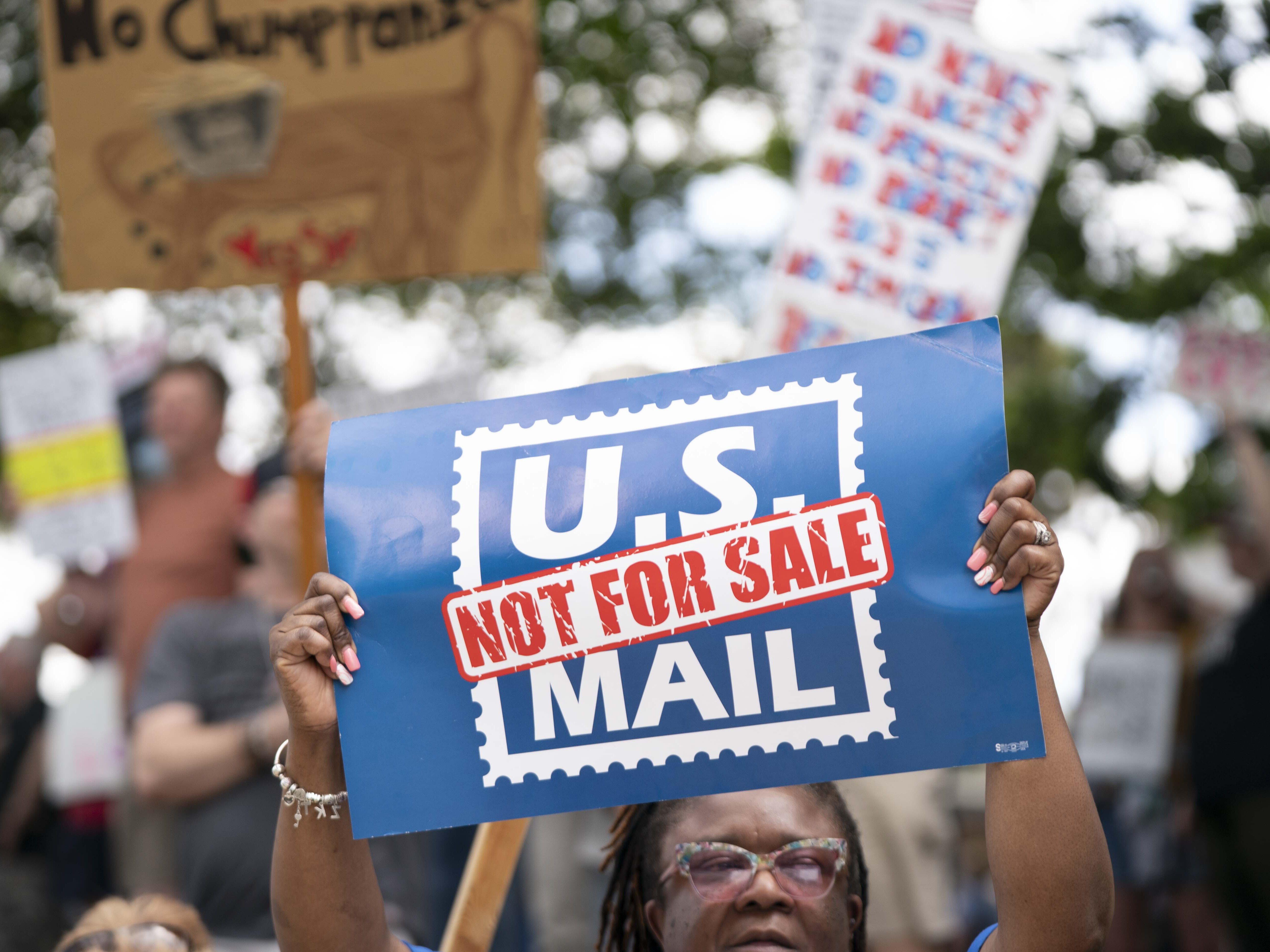 caption: A demonstrator holds a sign that says "U.S. MAIL NOT FOR SALE" during an April protest in Columbia, S.C.