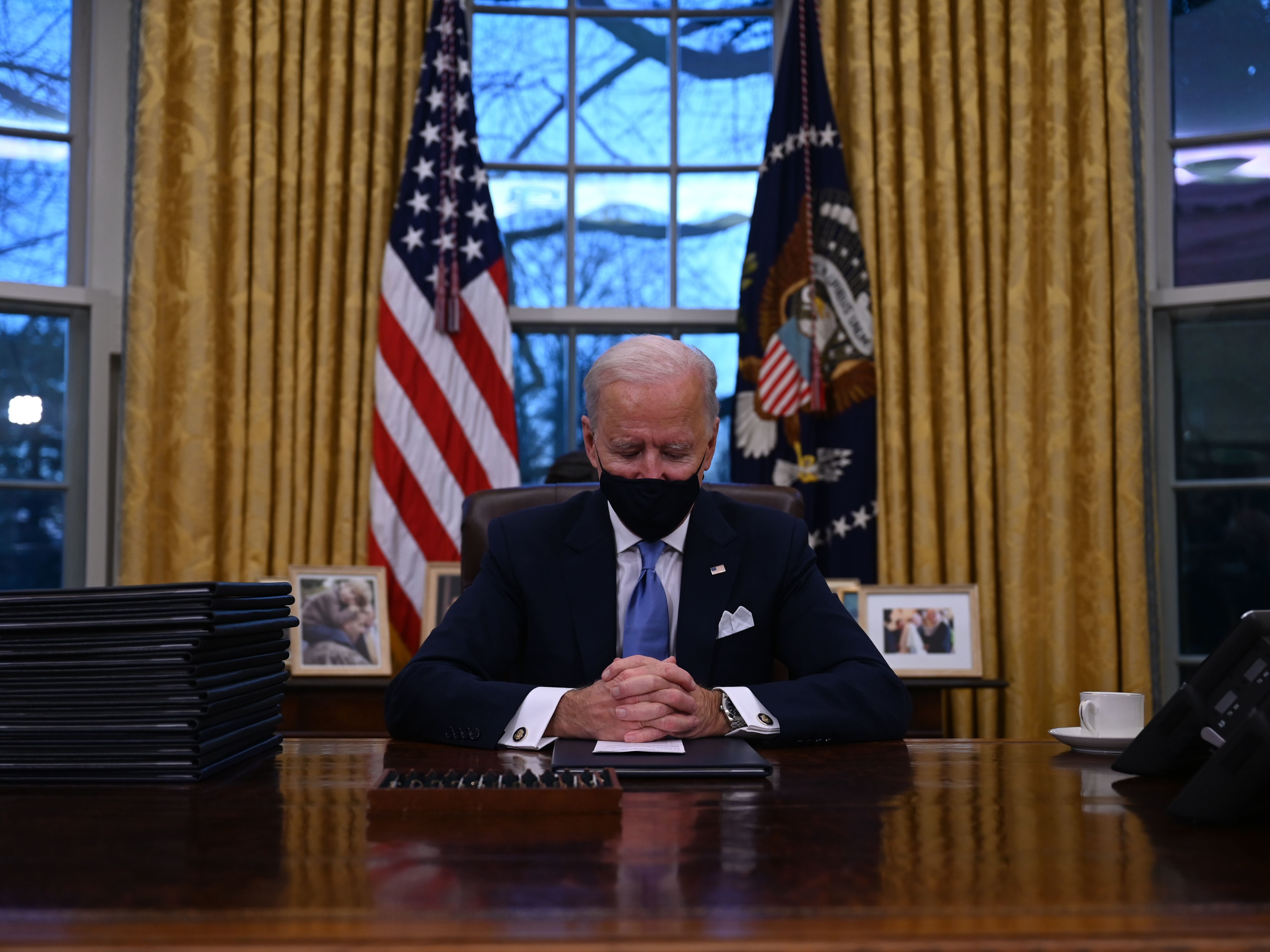 caption: President Biden sits in the Oval Office at the White House after being sworn in as the 46th president of the United States on Wednesday.