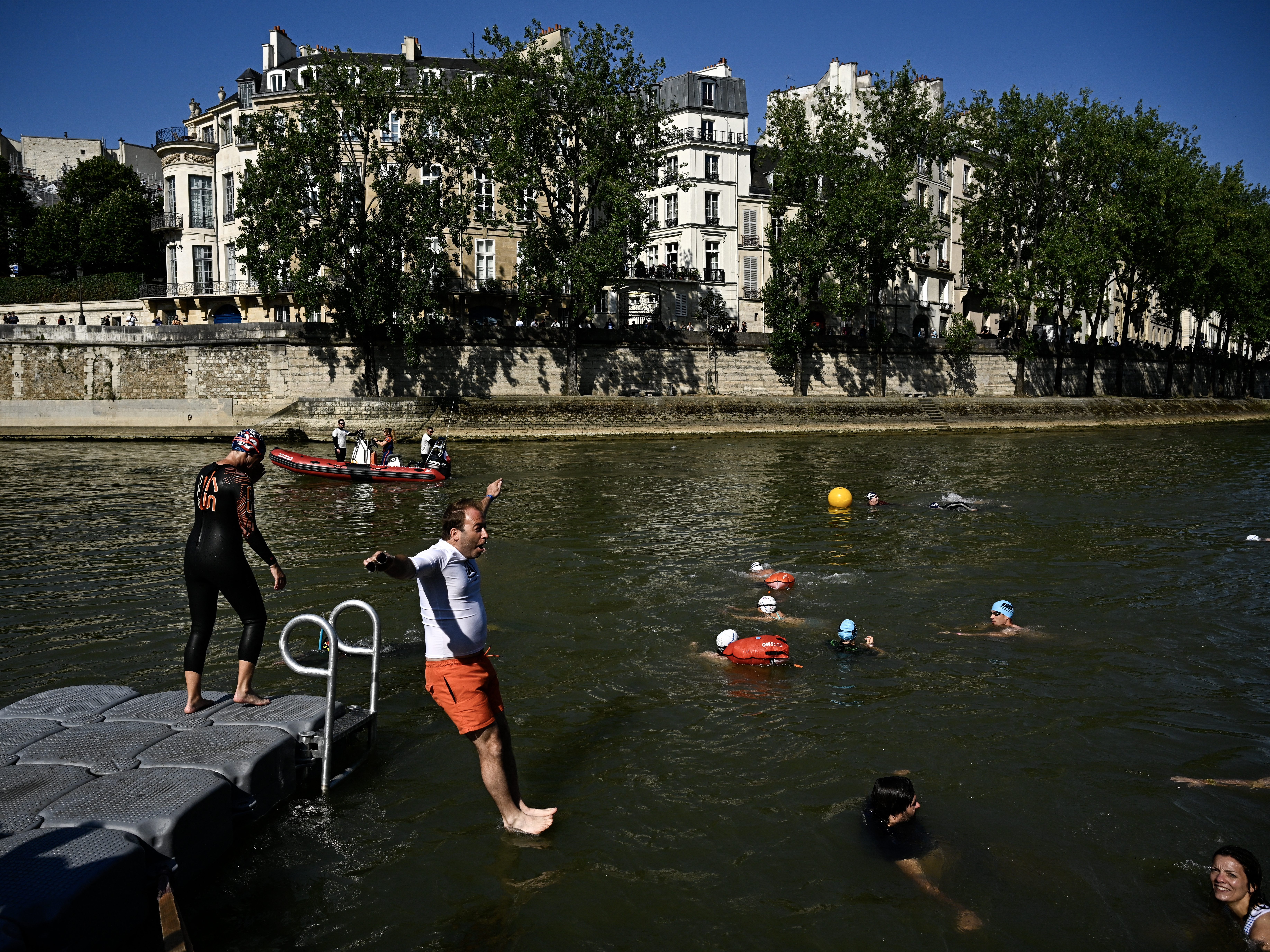 caption: People jump into the Seine River in Paris on July 17, after Mayor Anne Hidalgo swam in the river to demonstrate that it is clean enough to host the outdoor swimming events at the Paris Olympics later this month.
