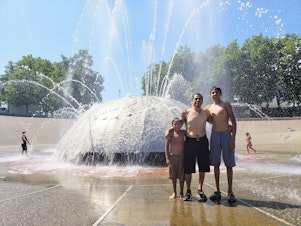 caption: Omar Rodriguez and his sons, Julian and Nathaniel, run through International Fountain on Monday, August 14, 2023.
